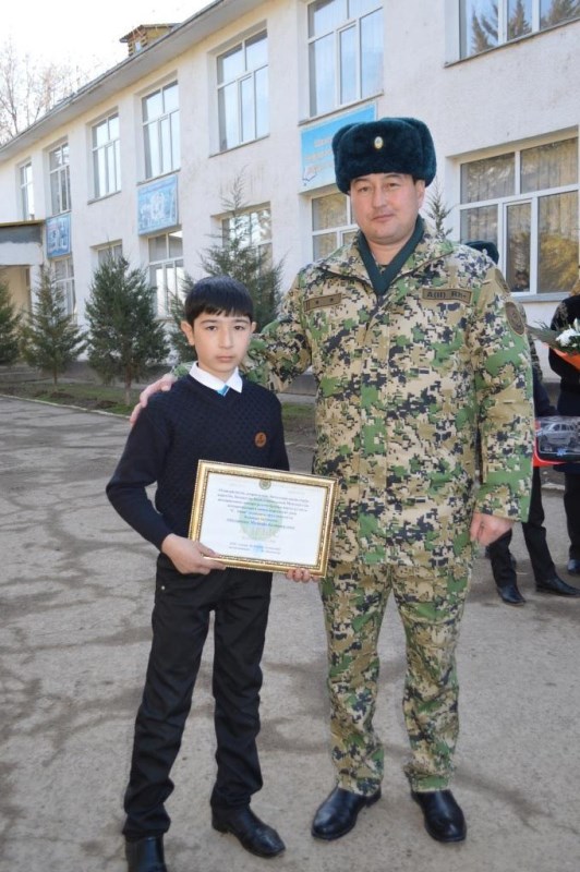 Мустафа Абдукаримов стоит рядом с пограничником и держит в руках Почётную грамоту.